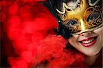 Beautiful young woman in carnival mask over red background