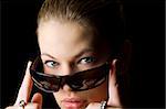 studio shot on black background of seductive girl taking off sunglasses looking in camara