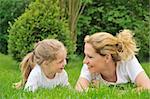 Young mother and daughter laying on the grass