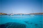 Boats moored in the crystal clear waters of the Blue Lagoon on the island of Comino in Malta.