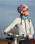 Active young woman with her bicycle. Smiling and looking at the sun