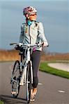 Active young woman with her bicycle. Smiling and looking at the sun