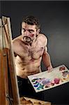 Seminude artist paints on an easel