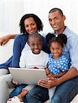 Smiling Afro-american family using a laptop on the sofa