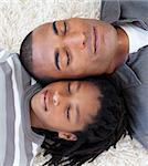 Portrait of Afro-American father and son sleeping on the floor at home