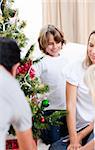 Happy parents and their children decorating a Christmas tree at home