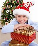 Happy little boy sitting on the floor with Christmas presents