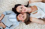 Mother and her daughter slepping on the floor with heads together