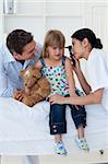 Doctor examining smiling child and mom