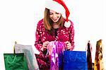 Young girl with santa cap checking into her shopping bags on a isolated white background