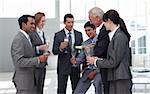 Senior businessman serving Champagne to his successful team in the office