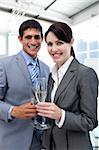 Two smiling colleagues drinking Champagne to celebrate a success