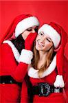 Two happy young Santa girl talking over red background .