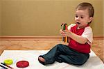 A thoughtful baby boy is sitting on the floor and thinking about his drawing