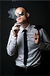 Young businessman smoking with coat on shoulder