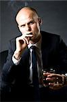 blue eyed businessman siting on a sofa and smoking a cigarette and drinking whiskey