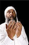 Stock image of Arab man praying over black background, selective focus on hands