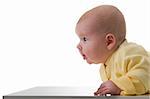 Young baby boy creeps on a table, over white background