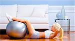 Side view of young woman in sportswear doing crunches in a living room.  Horizontal shot.