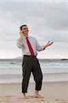 Businessman talking on cell phone while smiling and gesturing on a beach