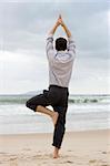 Businessman doing relaxation exercises on a beach