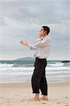 Businessman talking on cell phone on a beach while gesturing with his hand
