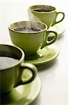 Three steaming mugs in a row in green colors