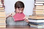 Crazy student gnaws red book between books