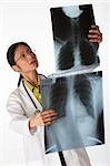 High angle view of an Asian female doctor looking at x-rays of lungs. Vertical shot. Isolated on white.