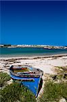 Old blue wooden boat on the sandy shore.