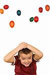 Boy with falling easter eggs protecting his head - isolated
