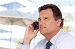 Confident, Handsome Businessman Smiles as He Talks on His Cell Phone Outdoors.