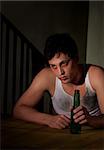 Depressed young man with bottle of beer