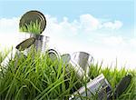 Empty food cans in grass with blue sky and clouds