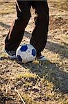 A shot of a boy's legs just as he is about to kick a soccer ball