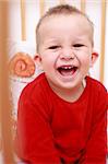 Portrait of cute newborn laughing  in crib