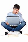 Young handsome student is sitting on floor with laptop on his knees and is tired of learning. Isolated on white.