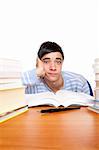 Young handsome student sitting on a desk between study books and looks frustrated. Isolated on white.
