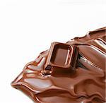 Melting piece of dark chocolate on white background