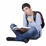 Young contemplative male student sitting on floor with book. Isolated on white.