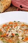 Chicken soup with pieces of meat, carrot, noodles and parsley