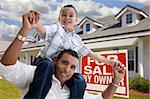 Excited Hispanic Father and Son with For Sale By Owner Sign in Front of House.