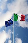 Italian and european flags on a high pole moved by wind