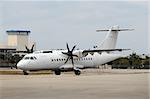 White unmarked turboprop airplane taxiing on the ground