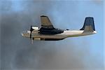 Retro military propeller airplane flying through smoke