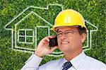 Contractor in Hardhat on His Cell Phone Over House Icon and Blurry Grass.