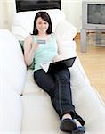 Femme joviale, magasinage en ligne étendu sur un canapé à la maison