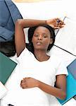 Young student doing her homework lying on a bed at home