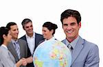 Happy businessman holding a globe in front of his team against a white background