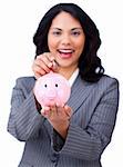 Self-assured young businesswoman saving money in a piggybank against a white background